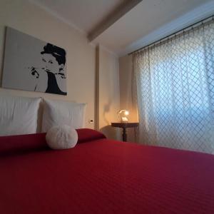 Un dormitorio con una cama roja con un osito de peluche. en la passeggiata, en Lido di Ostia