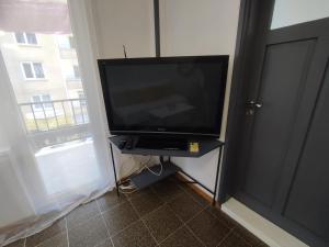a flat screen tv sitting on a stand next to a window at Апартамент Фамилия 100м от морето в Равда in Ravda