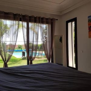 a bedroom with a bed and a large window at Exceptionnelle Villa duplex 3 ch avec piscine privée dans résidence fermée in Riaïna +10 photos