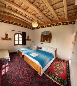 1 dormitorio con 2 camas y techo de madera en Hotel Awayou en Bou Tharar