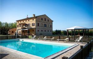 a swimming pool with chairs and a building in the background at 6 Bedroom Awesome Home In Treia in Appignano