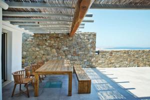 una mesa de madera y sillas en una habitación con una pared de piedra en Boutique Mykonos Villa - Heated Hot-Tub - Wonderful views - Villa Heart - Agia Sofia en Dexamenes