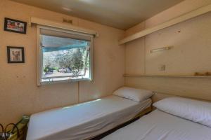 two beds in a small room with a window at Casetta Mobile al mare di Cavo in Cavo