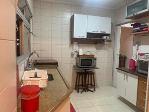 a small kitchen with a sink and a microwave at Apartamento Astúrias a menos de 50m da praia in Guarujá