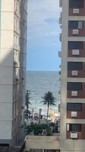 een uitzicht op het strand tussen twee gebouwen bij Apartamento Astúrias a menos de 50m da praia in Guarujá