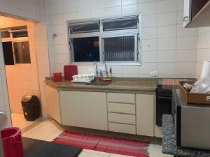 uma cozinha com um lavatório e uma janela em Apartamento Astúrias a menos de 50m da praia no Guarujá
