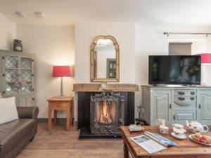a living room with a fireplace with a tv and a couch at Gate Lodge in Fettercairn