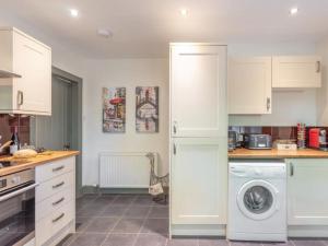 a kitchen with white cabinets and a washing machine at Gate Lodge in Fettercairn