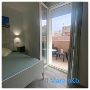 een slaapkamer met een bed en een glazen schuifdeur bij Il mare b&b in Quartu SantʼElena