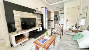 uma sala de estar com um sofá e uma televisão de ecrã plano em Apto Próximo a Vila Germânica em Blumenau