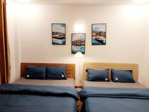 dwa łóżka w pokoju z obrazami na ścianie w obiekcie Da Tree Homestay w mieście Hanoi