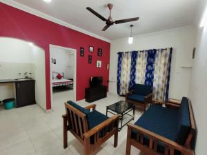 a living room with two chairs and a red wall at 2Bhk Apartments in Old Goa
