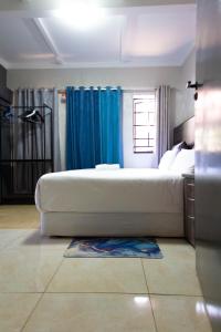 ein großes weißes Bett in einem Schlafzimmer mit blauen Vorhängen in der Unterkunft Latona Guest House in Johannesburg