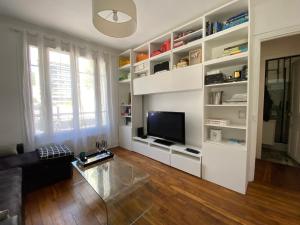 a living room with white shelves and a tv at Paris en 10 min, T3 dans le centre ville de Puteaux in Puteaux