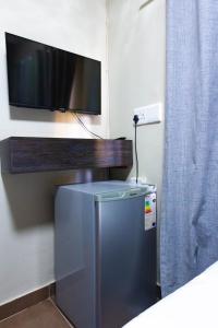 einen TV an einer Wand über einem kleinen Kühlschrank in der Unterkunft Latona Guest House in Johannesburg