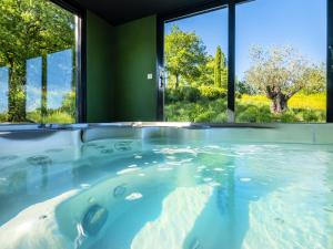a hot tub in a room with large windows at Studio avec piscine partagee sauna et wifi a Forcalquier in Forcalquier