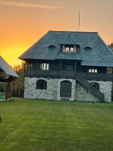 a stone house with a roof on a grass field at La Patru Daci in Ocna Şugatag