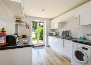 a kitchen with white cabinets and a washer and dryer at Bay Retreat Villas in Saint Merryn