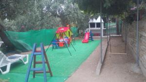 einen Spielplatz mit Stühlen und einer Rutsche auf einem grünen Boden in der Unterkunft Vaso Studios in Aliki