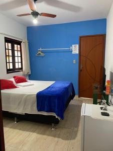 een blauwe slaapkamer met een bed en een blauwe muur bij Quarto com banheiro no térreo in Araruama