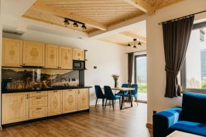 a kitchen with wooden cabinets and a table with chairs at Apartamenty Górajski Spa in Kościelisko