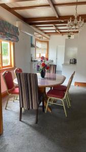 une table à manger avec des chaises et un vase de fleurs dans l'établissement Knights rd beauty, à Lower Hutt
