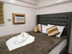 a bedroom with a bed with a leather headboard and pillows at FB Dormitel Suites in Cagayan de Oro