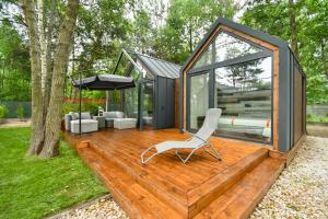 a tiny house with a white chair on a deck at Leśne SPA pod Warszawą in Wólka Radzymińska