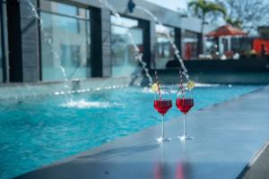 two glasses of red wine sitting next to a swimming pool at Indore Marriott Hotel in Indore