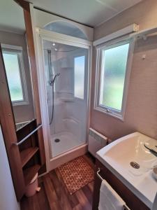 y baño con ducha y lavamanos. en Mobil Home proche de la mer, en Saint-Martin-Plage