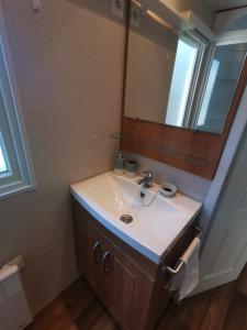 La salle de bains est pourvue d'un lavabo et d'un miroir. dans l'établissement Mobil Home proche de la mer, à Saint-Martin-Plage