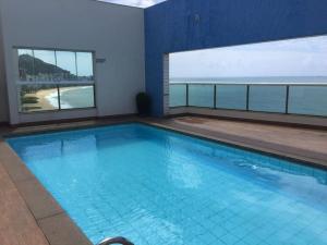 a large swimming pool with a view of the ocean at Ocean Flat 1006 in Vila Velha