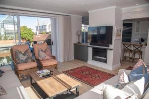 a living room with a couch and a tv at Waterfront- C25 Knysna Quays with pool in Knysna