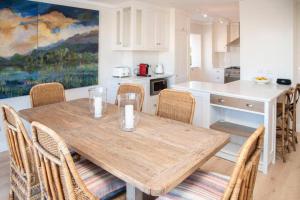 a kitchen with a wooden dining table and chairs at Waterfront- C25 Knysna Quays with pool in Knysna