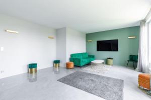 sala de estar con sofá verde y TV de pantalla plana en Magnifique Appartement avec vue sur la Tour Eiffel en Bagneux