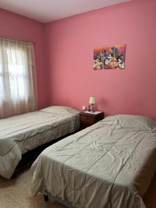 2 camas en una habitación con paredes rosas en Casa Rústica Norteña Candy Con Parking, en Salta