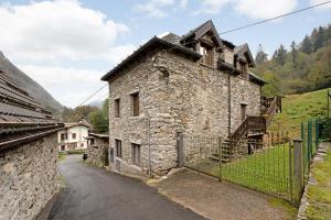 an old stone house on a street with a fence at Titti in Anzino