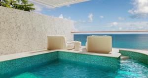 einen Pool mit zwei Stühlen und das Meer in der Unterkunft Sandals Regency La Toc All Inclusive Golf Resort and Spa - Couples Only in Castries