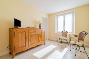 a living room with a tv on a wooden cabinet and two chairs at Le Claudel - Idéal pour découvrir les Vosges in La Bresse