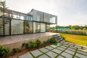 uma casa moderna com janelas de vidro e um relvado em Bliss Farm Stay- Tulip em Secunderābād