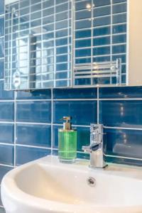 a bathroom sink with a green soap dispenser on it at Spacious 2 Bedroom Retreat In East Dulwich in London
