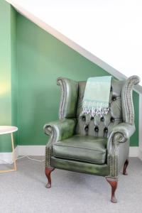 a green leather chair sitting in a living room at Spacious 2 Bedroom Retreat In East Dulwich in London