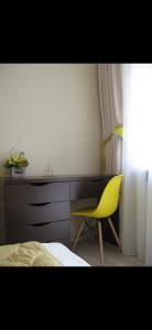 een slaapkamer met een gele stoel en een bureau bij Summer in Braşov