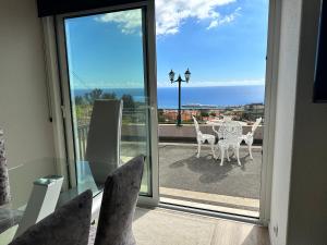 a balcony with chairs and a table with a view of the ocean at Casa de Ferias dos Marmeleiros in Funchal