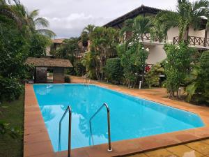 a large blue swimming pool in front of a building at Na Vila da Praia do Forte- BA, 2 quartos, piscina, 2 garagens in Praia do Forte