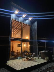 ein Haus mit einem Tisch und Stühlen auf einer Terrasse in der Nacht in der Unterkunft CABAÑAS LODGE LOS COIHUES 2 VALLE LAS TRANCAS/TERMAS DE CHILLAN /NEVADOS DE CHILLAN in Pinto