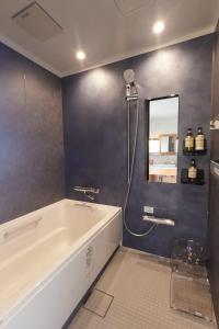 a bathroom with a bath tub and a mirror at Stay UWU 001 ステイ ウー 001 in Kochi