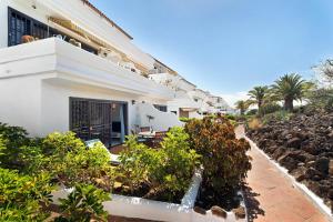 een wit gebouw met planten en een pad bij Blue Dream Pebble Beach in San Miguel de Abona