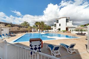 a swimming pool with chairs and a house at Blue Dream Pebble Beach in San Miguel de Abona