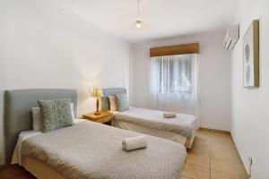 una piccola camera con due letti e una finestra di Directly to the Beach Two Bedrooms a Carvoeiro